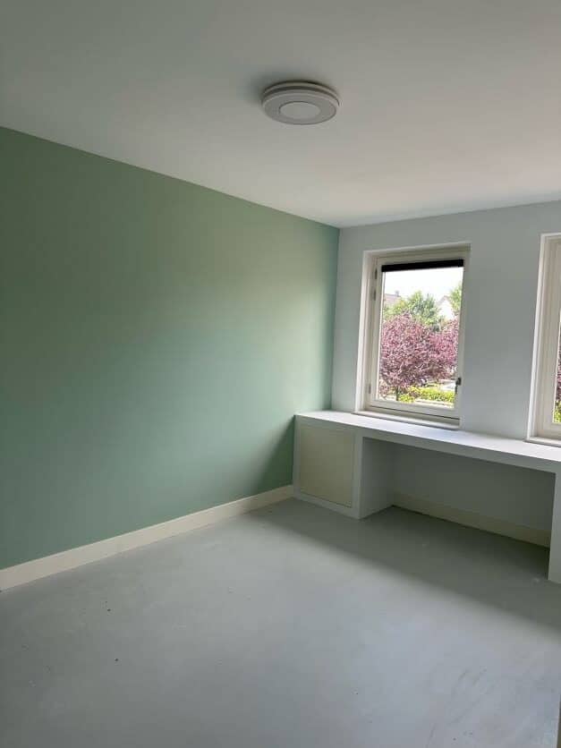 Groene binnenmuur strak geschilderd in lichte kamer