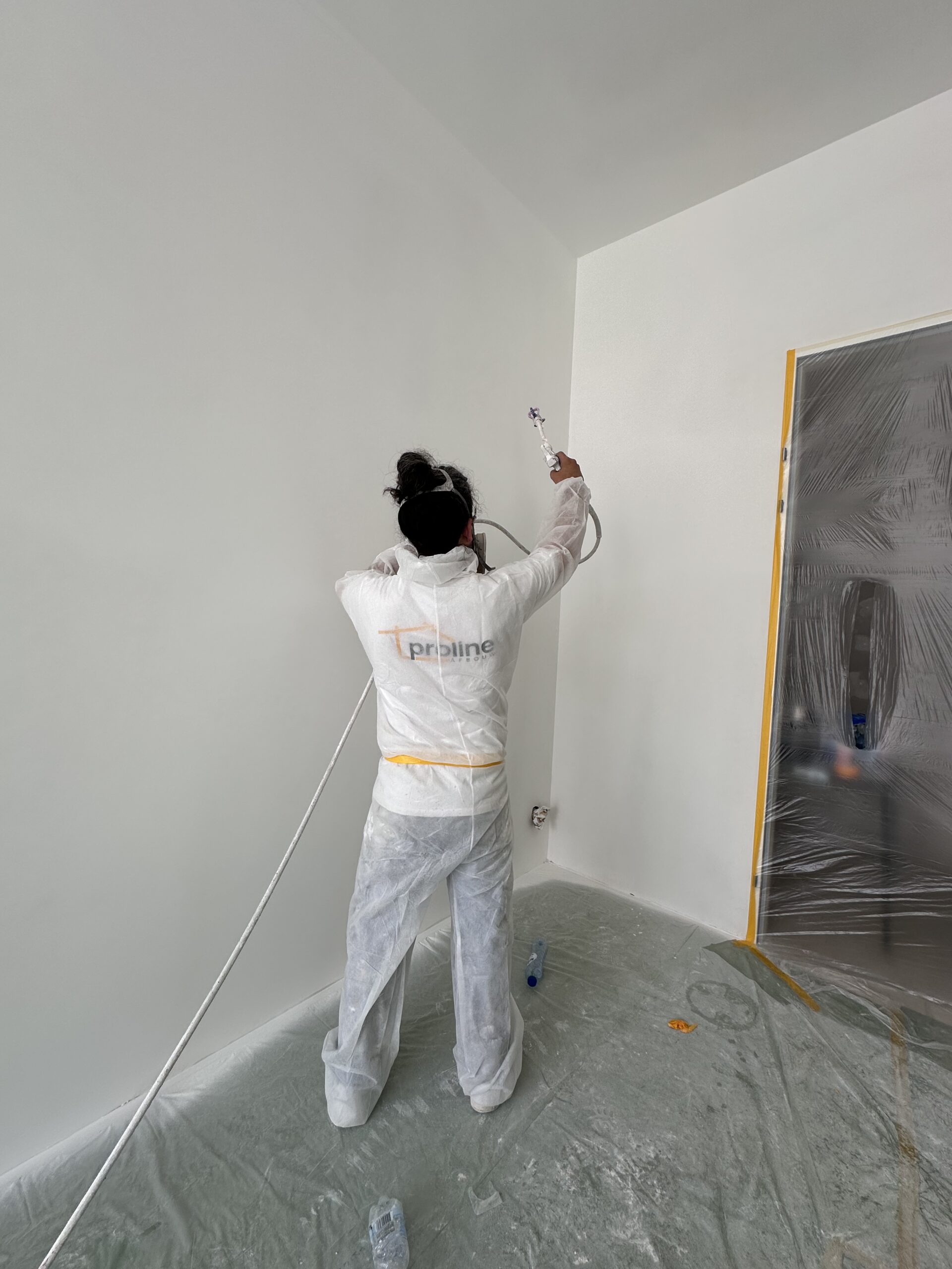 Witte wand voorbereid voor latex spuiten met afgeplakte vloer