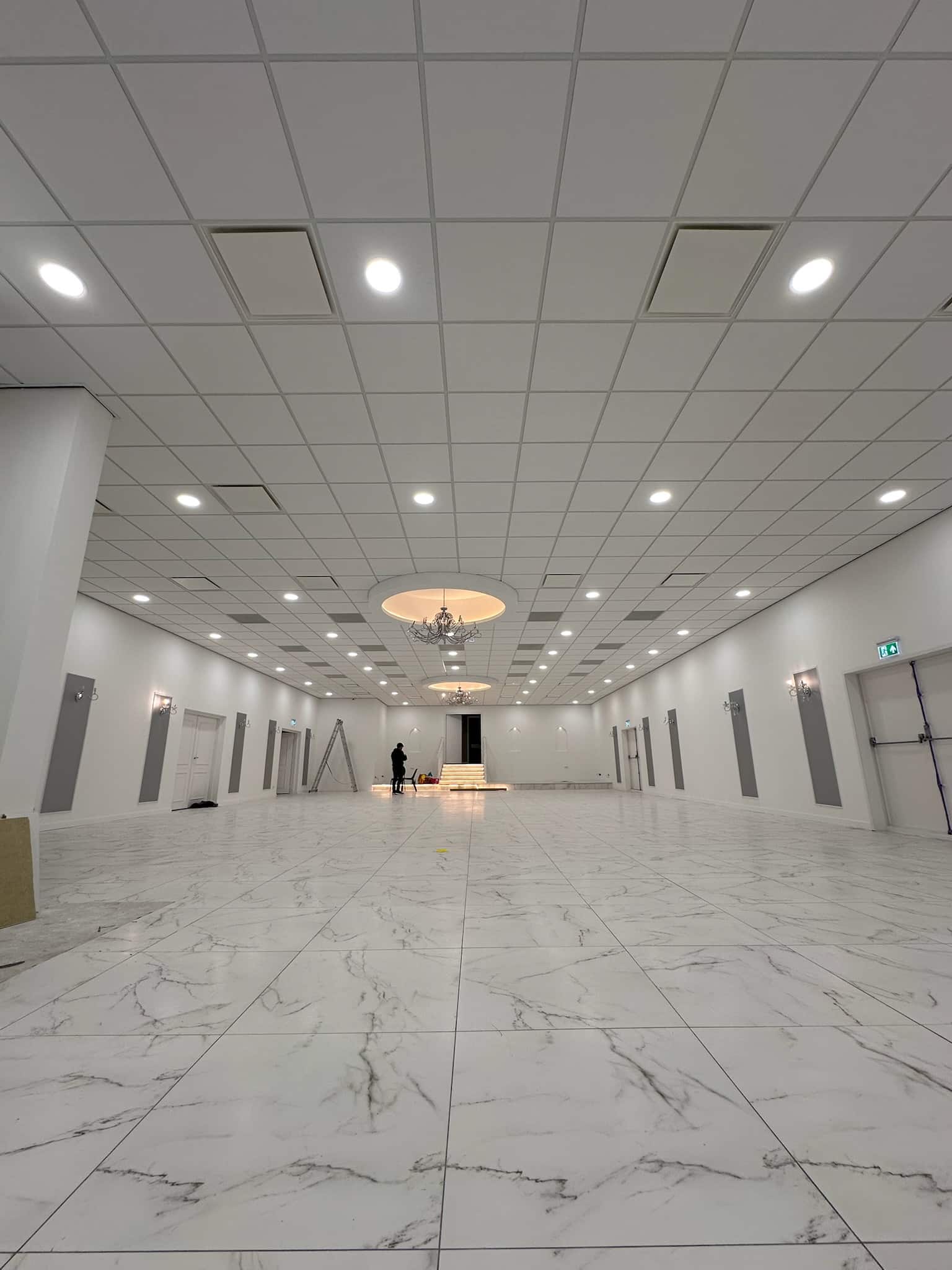 Latex spuiten nieuwbouw in grote lichte zaal met systeemplafond